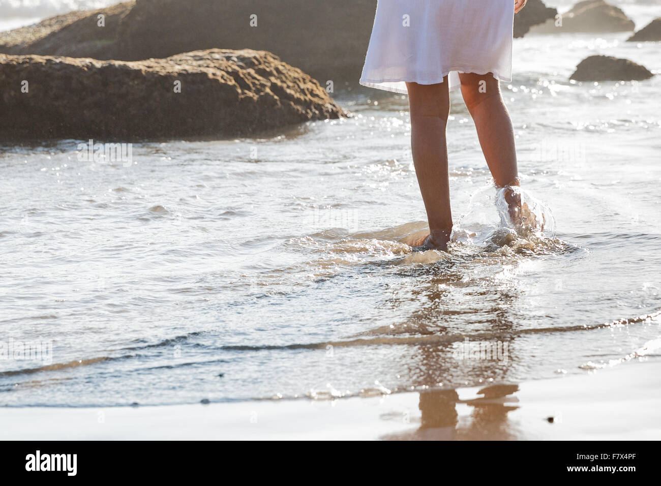 Chica caminando en el surf en la playa Foto de stock