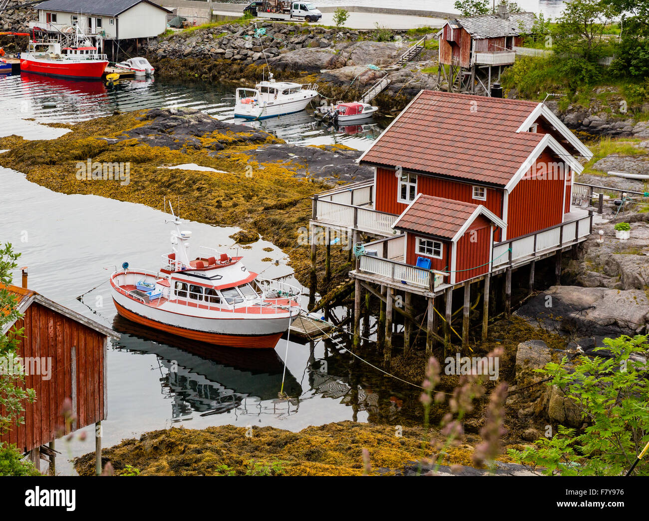 Pequeña casa sobre zancos y pequeño barco pesquero amarrado junto a Moskenes en el oeste de las Islas Lofoten Noruega Foto de stock