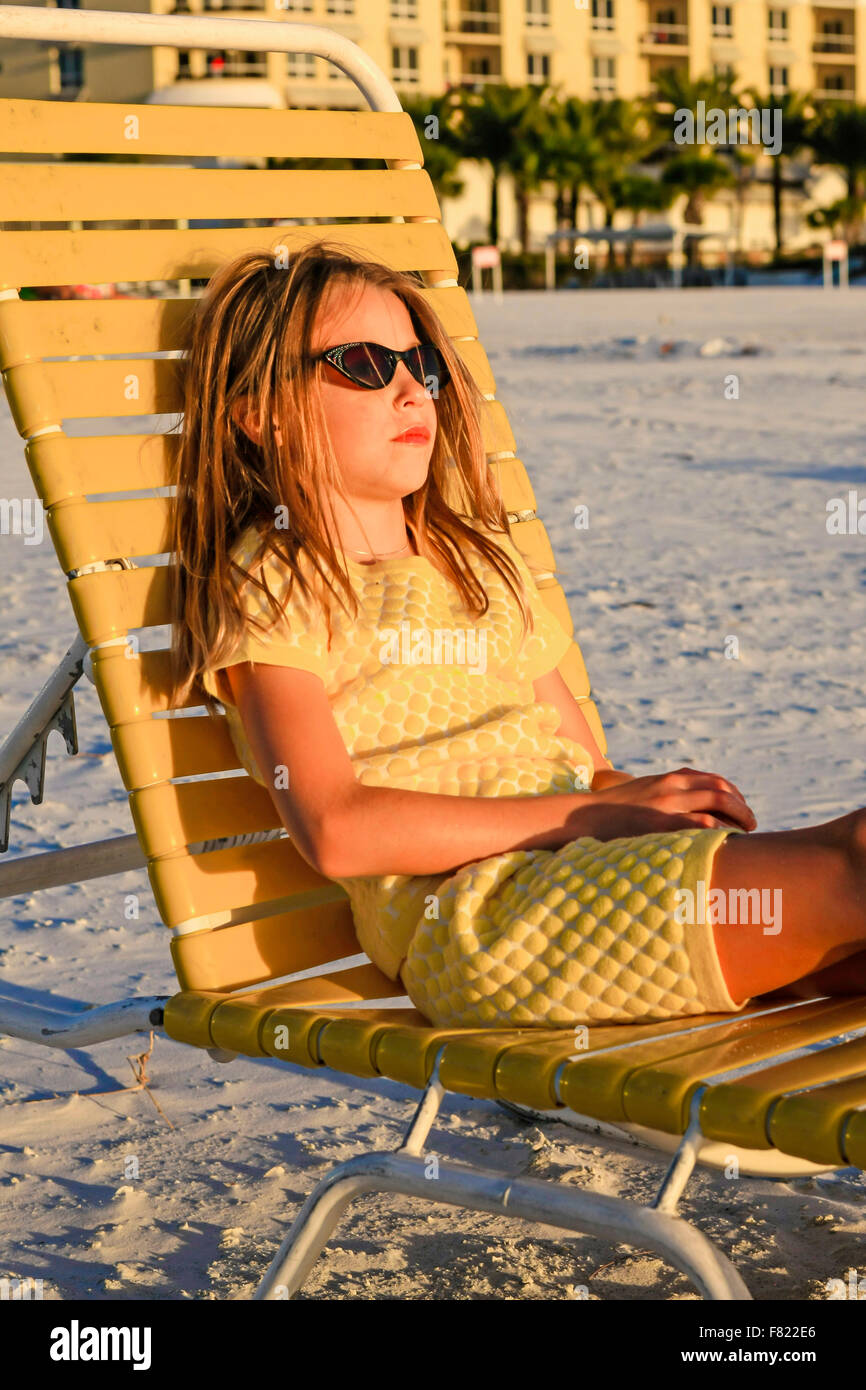 Jóvenes pre-adolescentes chica sentada en una tumbona en la playa viendo el  atardecer en Siesta Key, Florida Fotografía de stock - Alamy