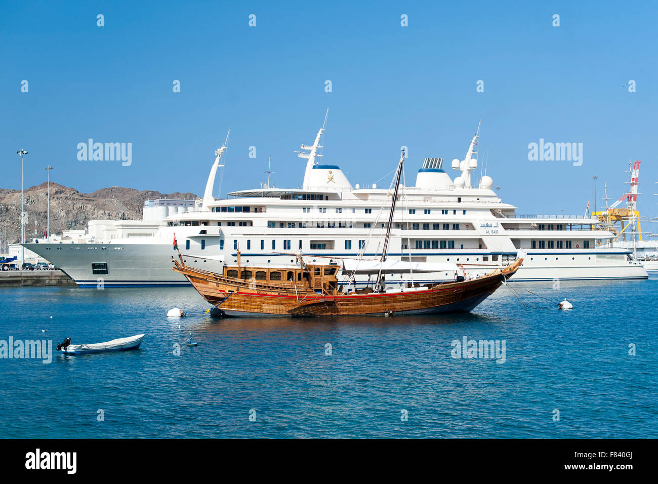 Barco de madera amarrado junto a la super yate del Sultán de Omán en Mutrah Harbor, Muscat. Foto de stock
