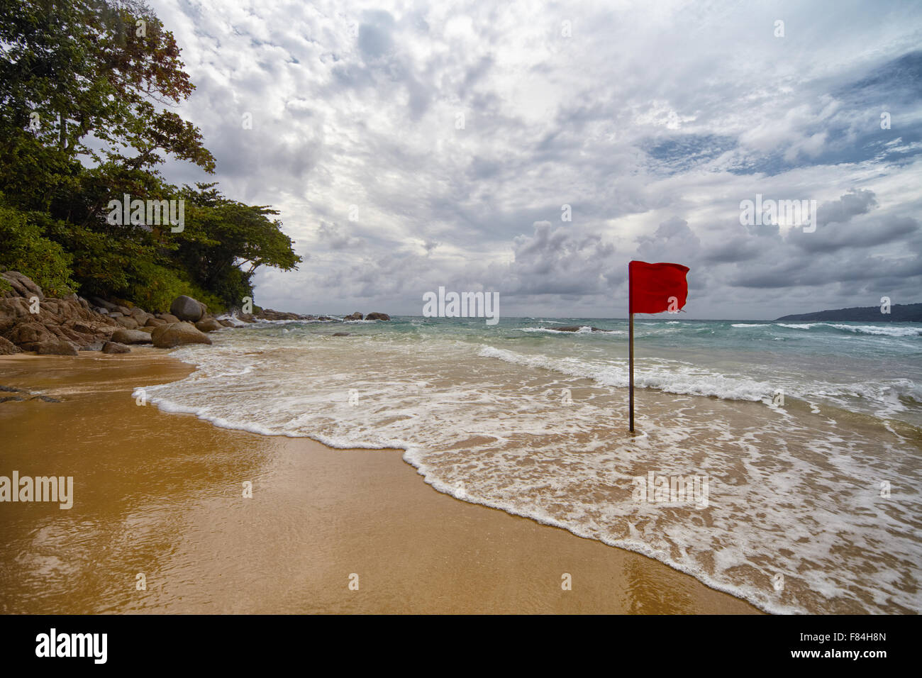 Bandera roja en una playa aislada en Tailandia wiyh un cielo nublado en la parte trasera del terreno. Foto de stock