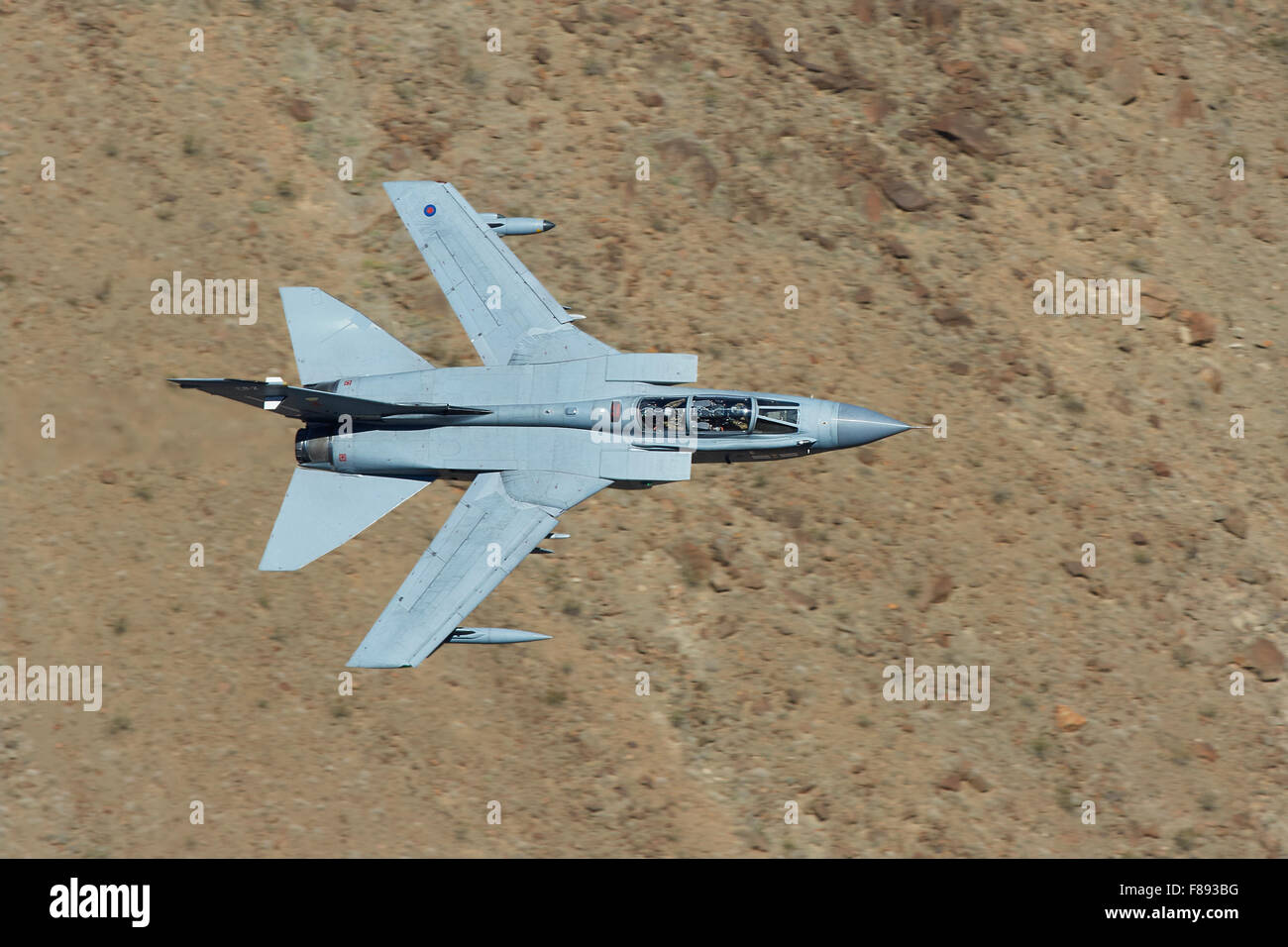 Royal Air Force jet de combate Tornado GR4 volando a muy bajo nivel a través de un valle desértico. Foto de stock