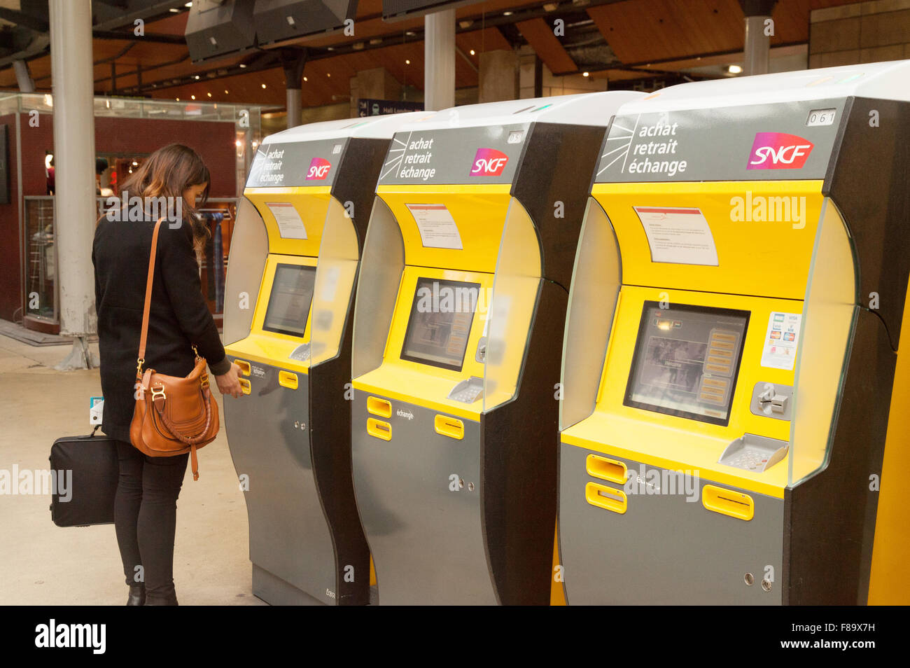 Una mujer compra un billete de tren en una máquina de billetes, la Gare du Nord, Paris Francia Europa Foto de stock