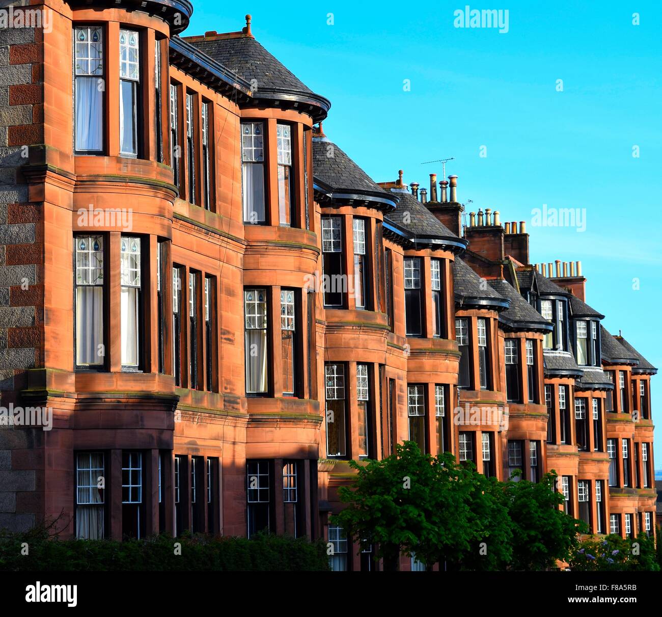 Fila de arenisca roja casón victoriano flats en dowanhill street en el West End de Glasgow mirando cuesta abajo en un día soleado Foto de stock