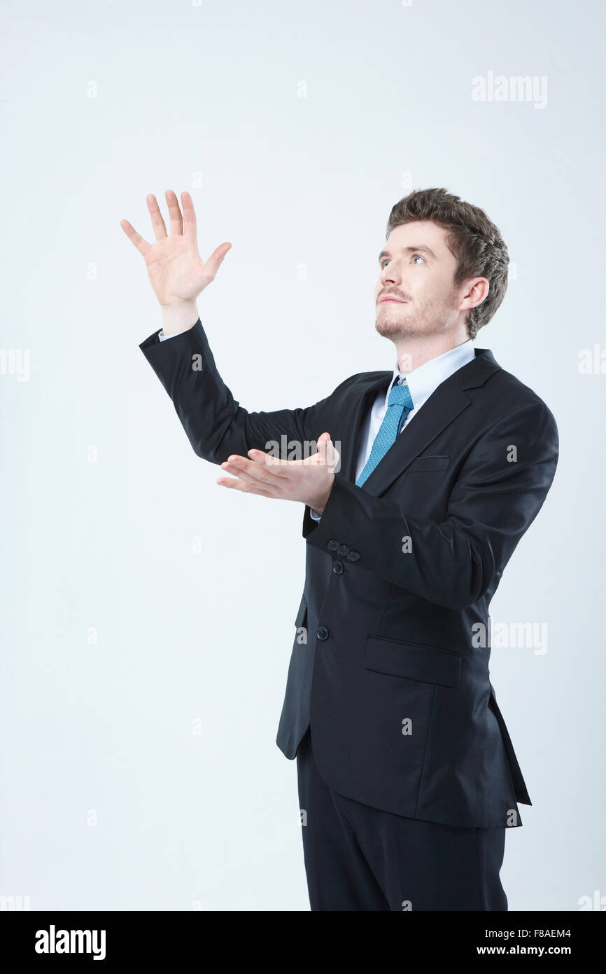 Hombre de negocios mirando hacia arriba con sus brazos abiertos verticalmente Foto de stock