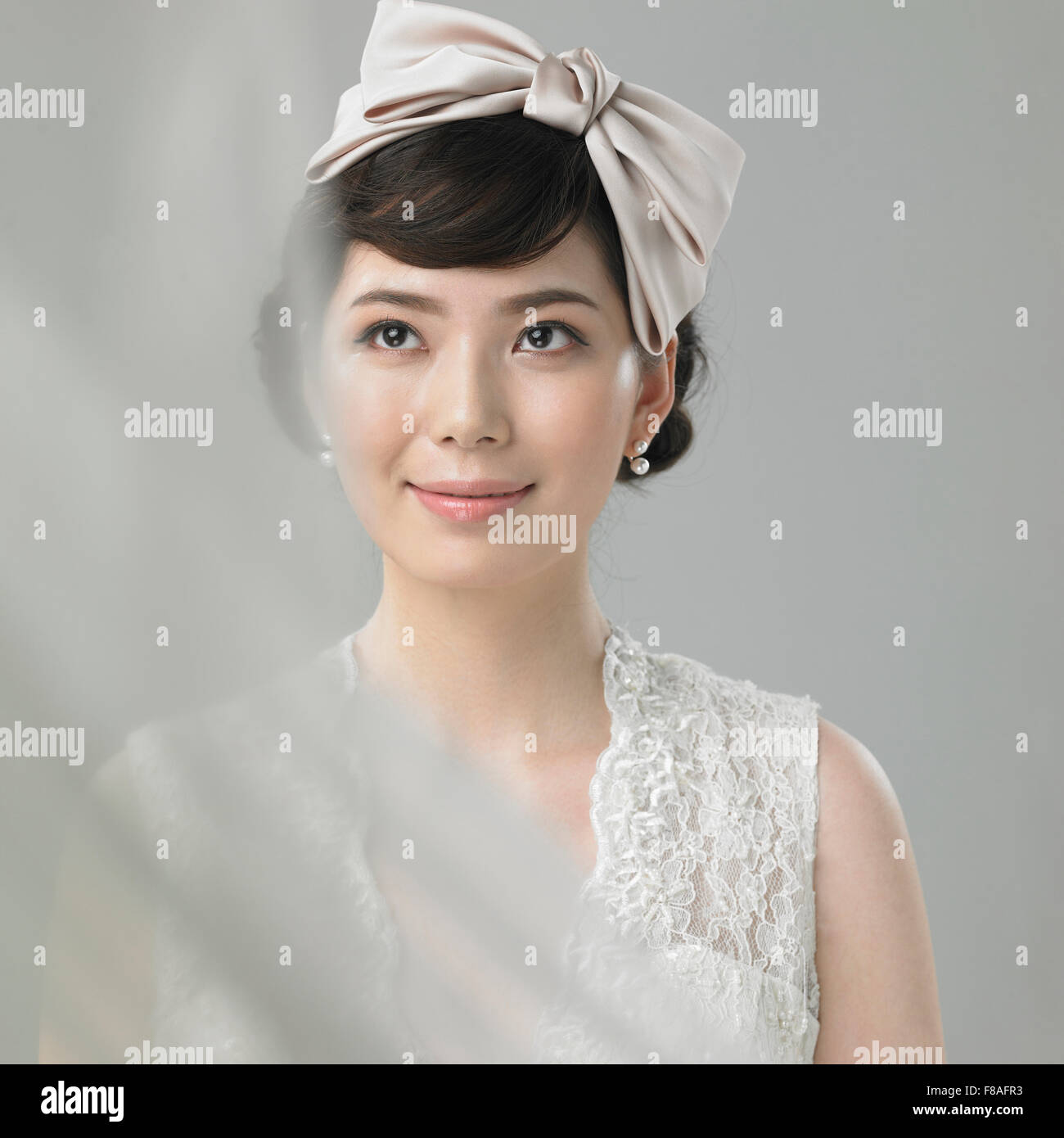 Mujer en traje de novia con cinta de pelo mirando hacia arriba Foto de stock