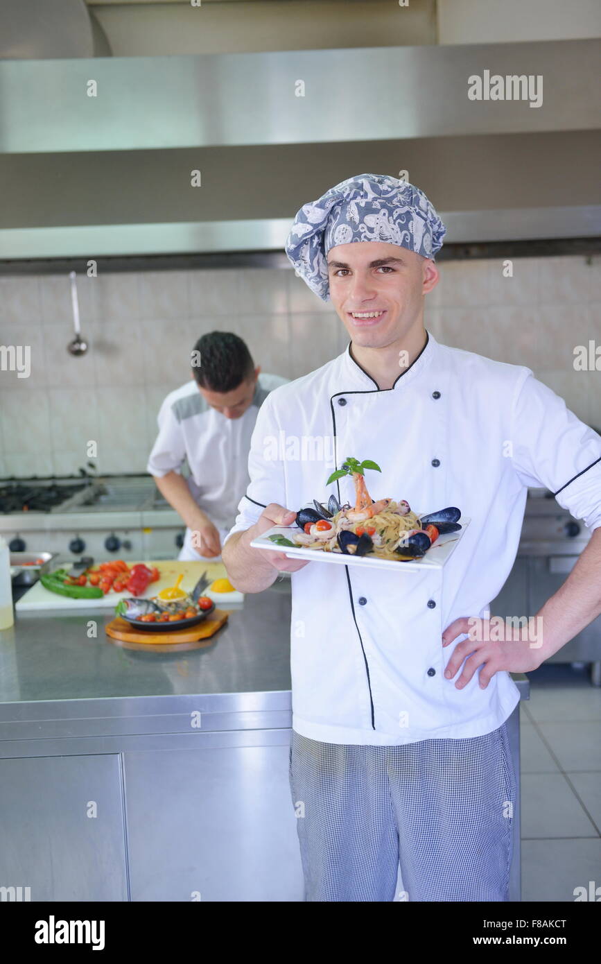 Chef guapo vestido de blanco uniforme decorando ensalada de pasta de  pescado y mariscos en la cocina moderna Fotografía de stock - Alamy