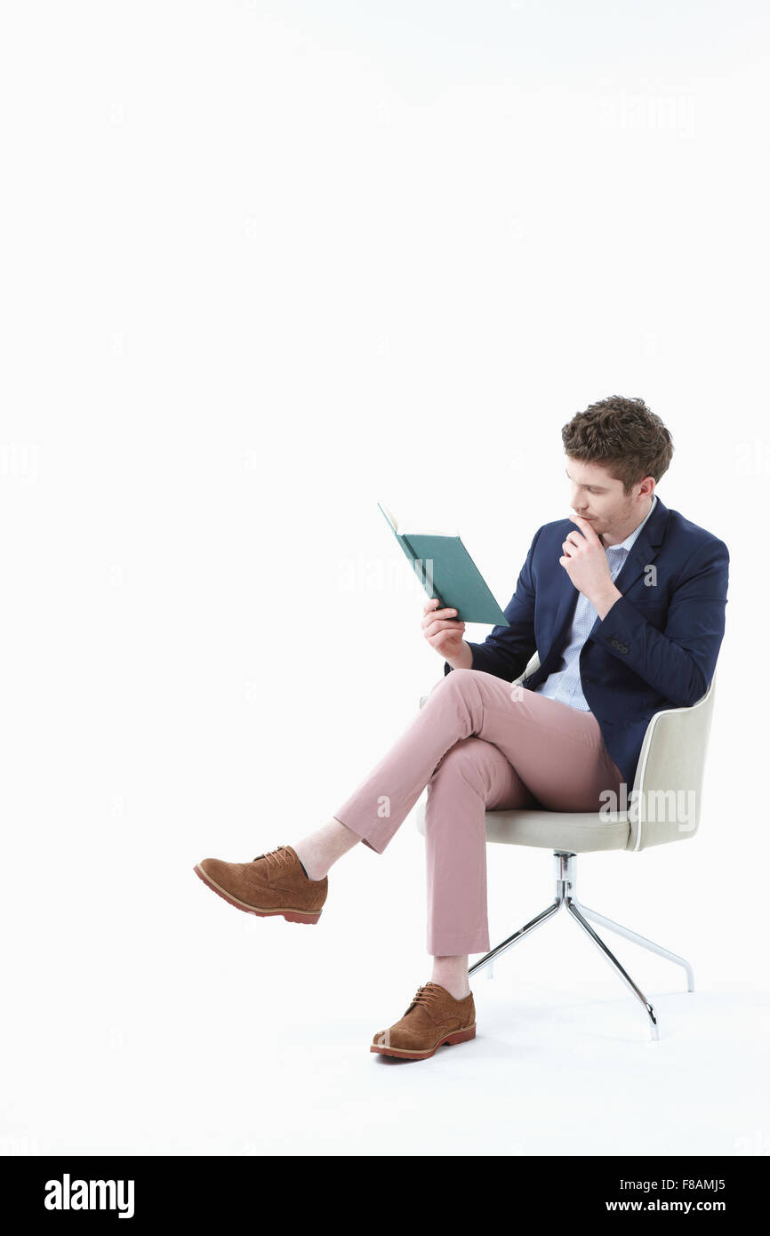 Empresario sentado en una silla con las piernas cruzadas y leer un su sobre su mano Fotografía de stock - Alamy