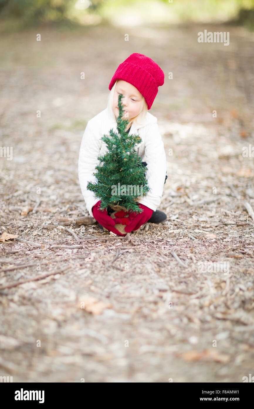 Baby Girl en rojo Mitones y cerca de un pequeño árbol de Navidad en el exterior Fotografía de stock - Alamy