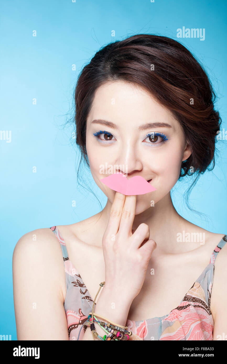 Mujer con línea blue eye make-up poniendo sus dedos conectados con el reborde con forma de adhesivo en sus labios y mirando hacia delante Foto de stock