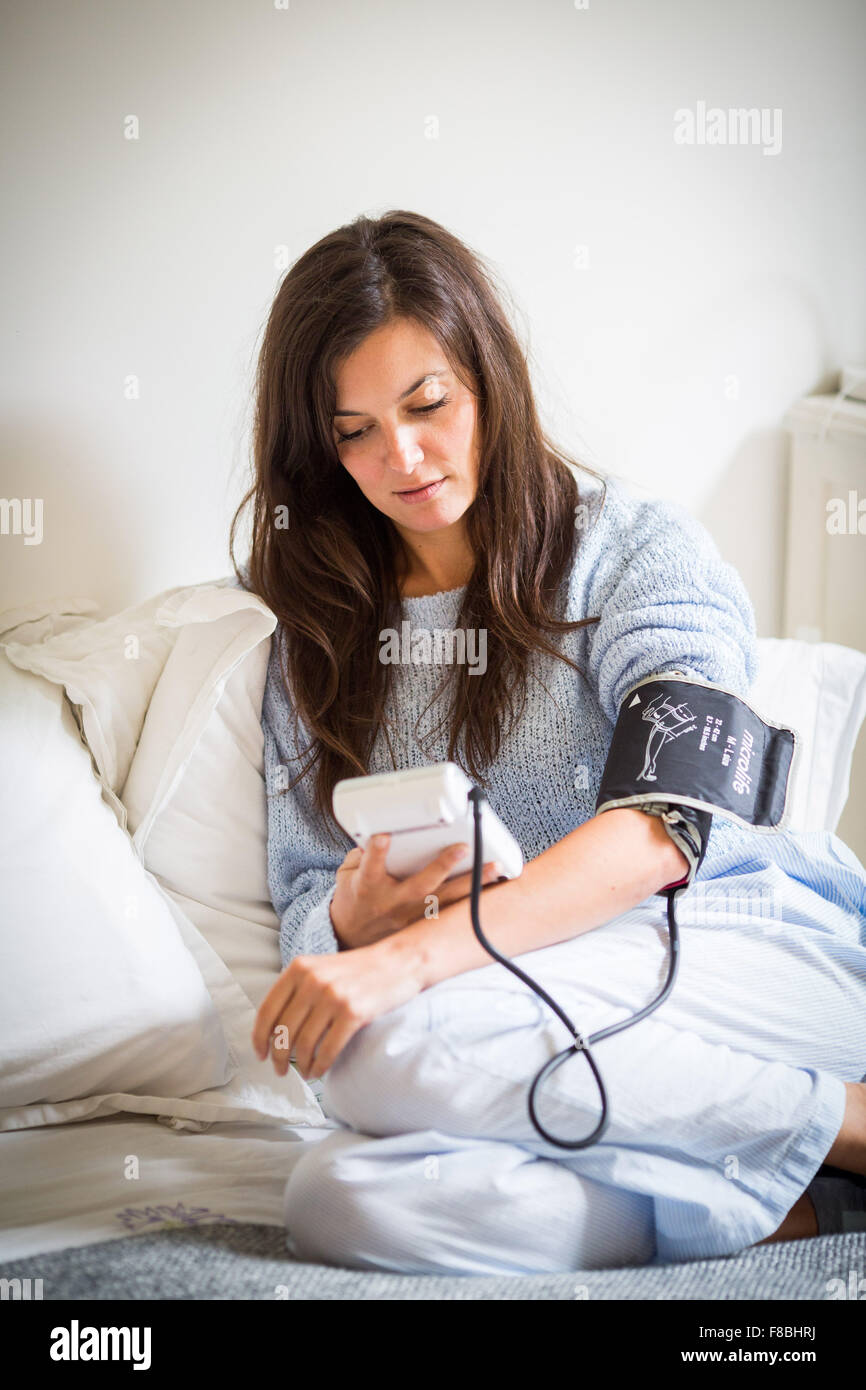 Mujer toma su presión arterial con un portátil de monitor de presión arterial. Foto de stock