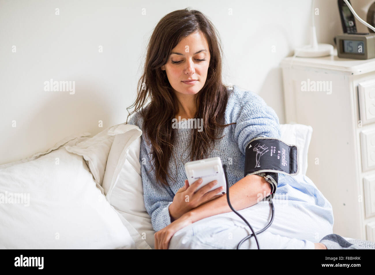 Mujer toma su presión arterial con un portátil de monitor de presión arterial. Foto de stock