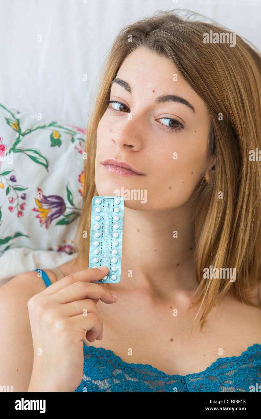 Mujer joven sosteniendo las píldoras anticonceptivas orales. Foto de stock