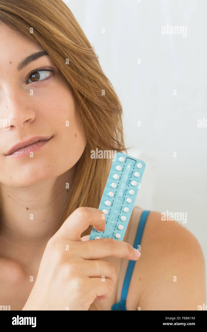Mujer joven sosteniendo las píldoras anticonceptivas orales. Foto de stock