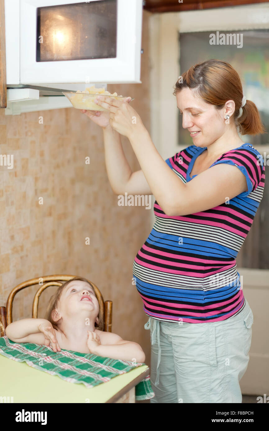 Mujer embarazada calienta los alimentos en el horno de microondas  Fotografía de stock - Alamy