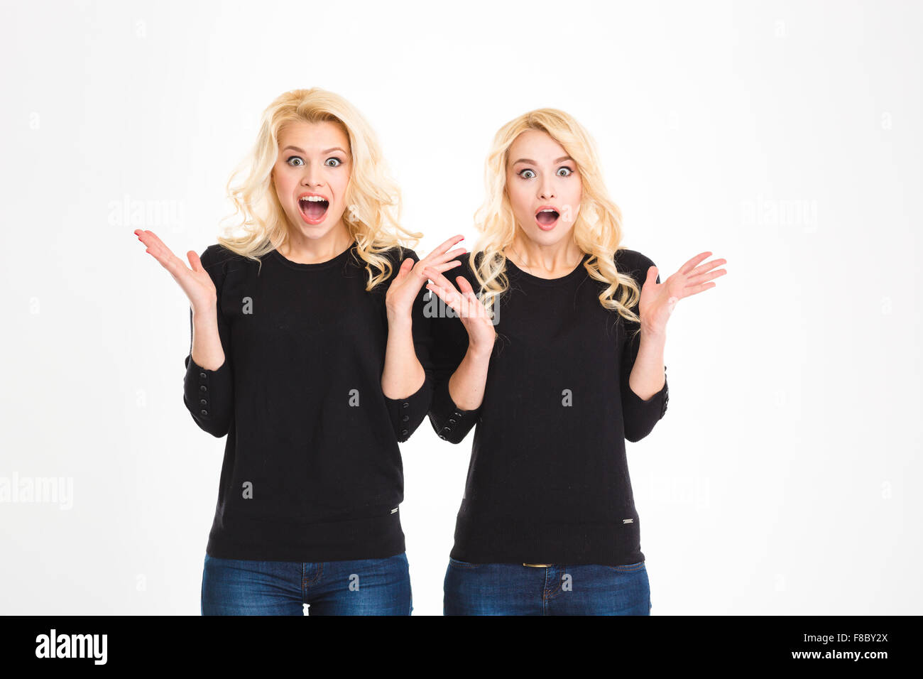 Dos hermanas divertida rubia conmocionó sorprendido gemelos aislado sobre fondo blanco. Foto de stock