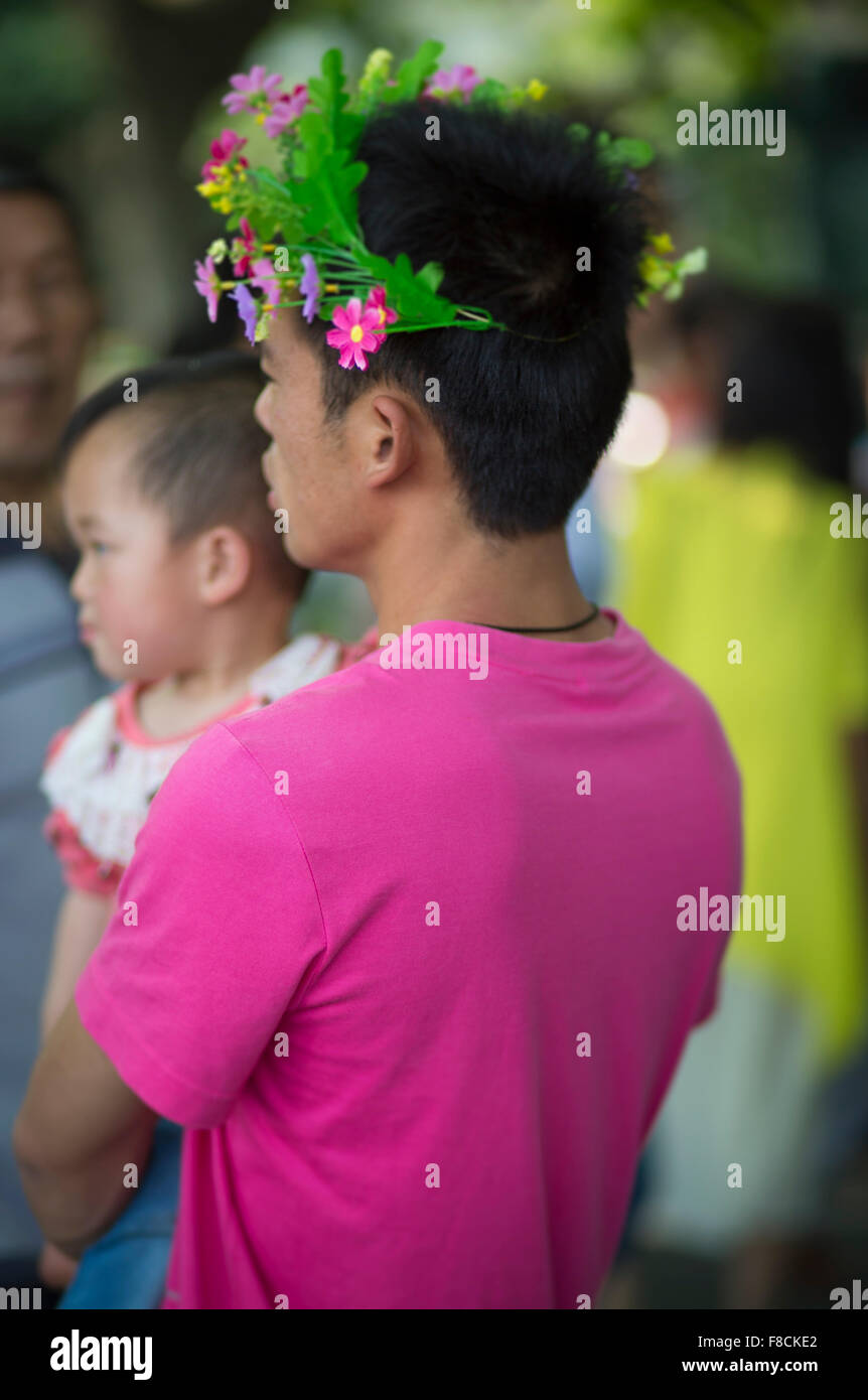 Hombre chino vistiendo la camiseta con el color verde de flores alrededor de su cabeza Foto de stock