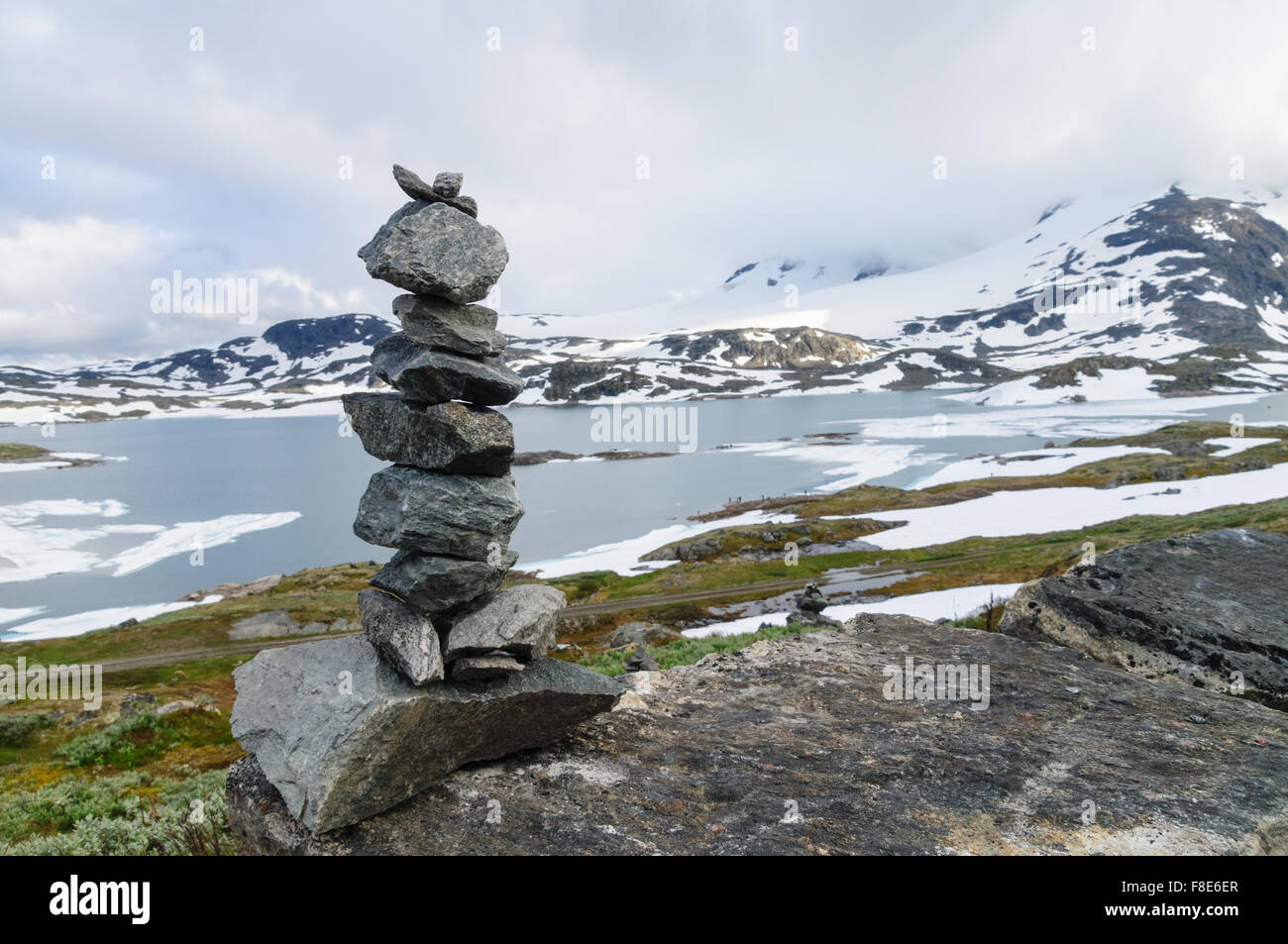 Pila de equilibrado de piedras contra el fondo borroso de higland lago y montañas nevadas Foto de stock