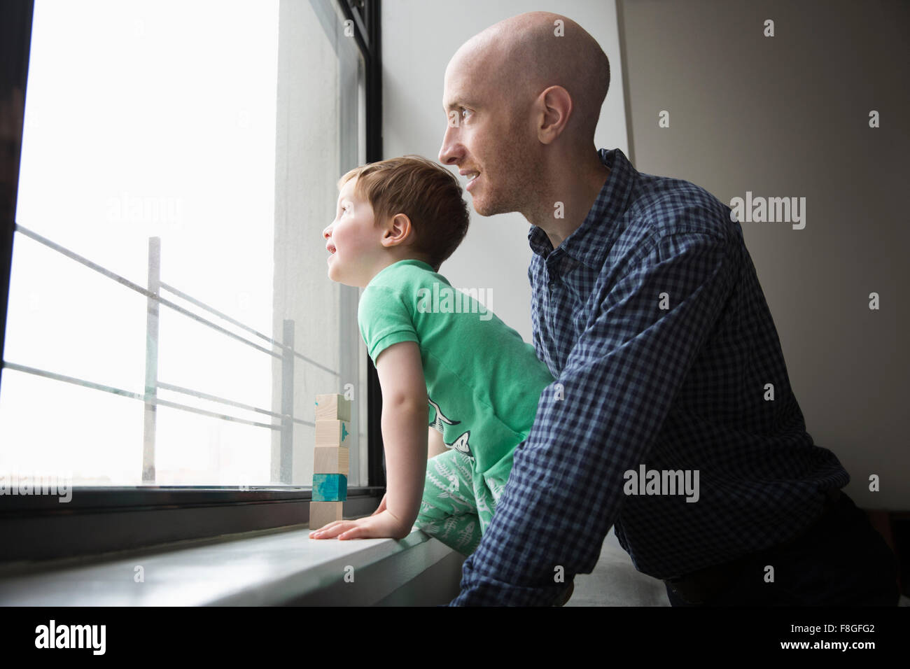 Padre e hijo mirando por la ventana Foto de stock