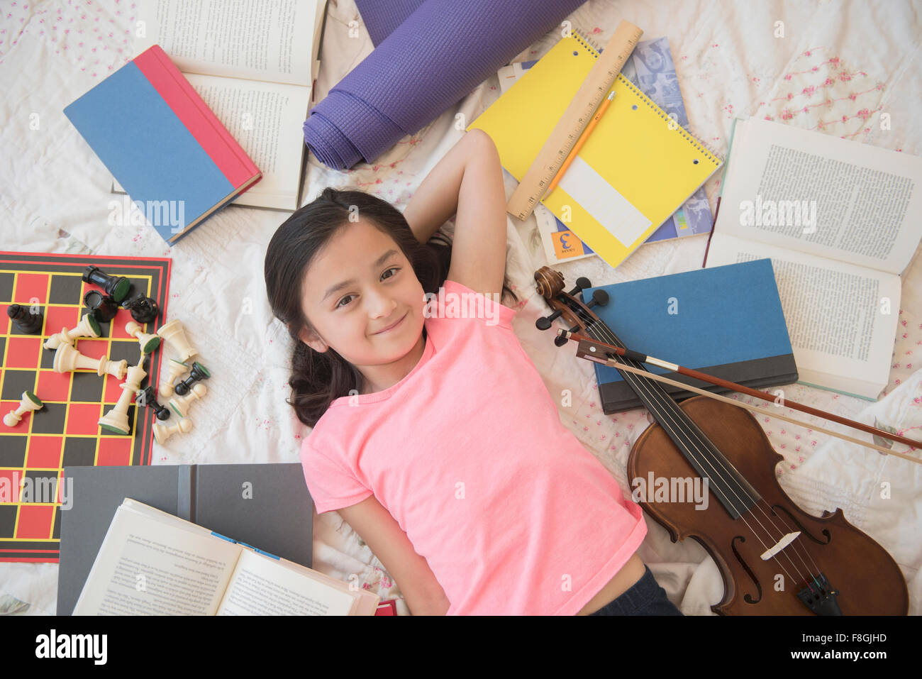 Chica colocando en el suelo con pasatiempos y deberes Foto de stock