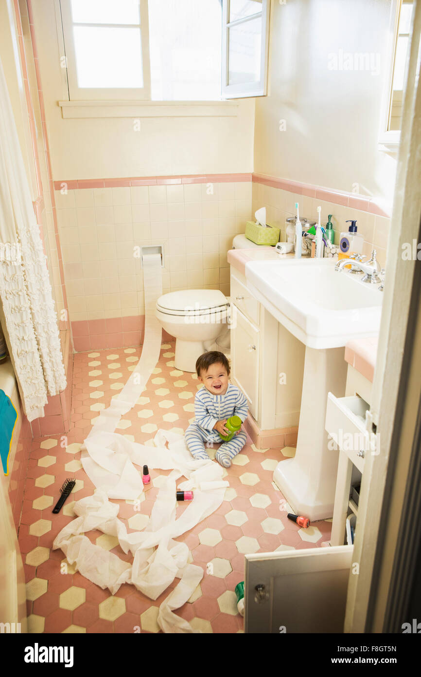 Baby Boy jugando en el cuarto de baño desordenado Foto de stock