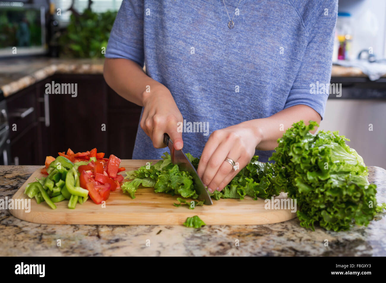 Mujer de raza mixta picar las verduras en la cocina Foto de stock