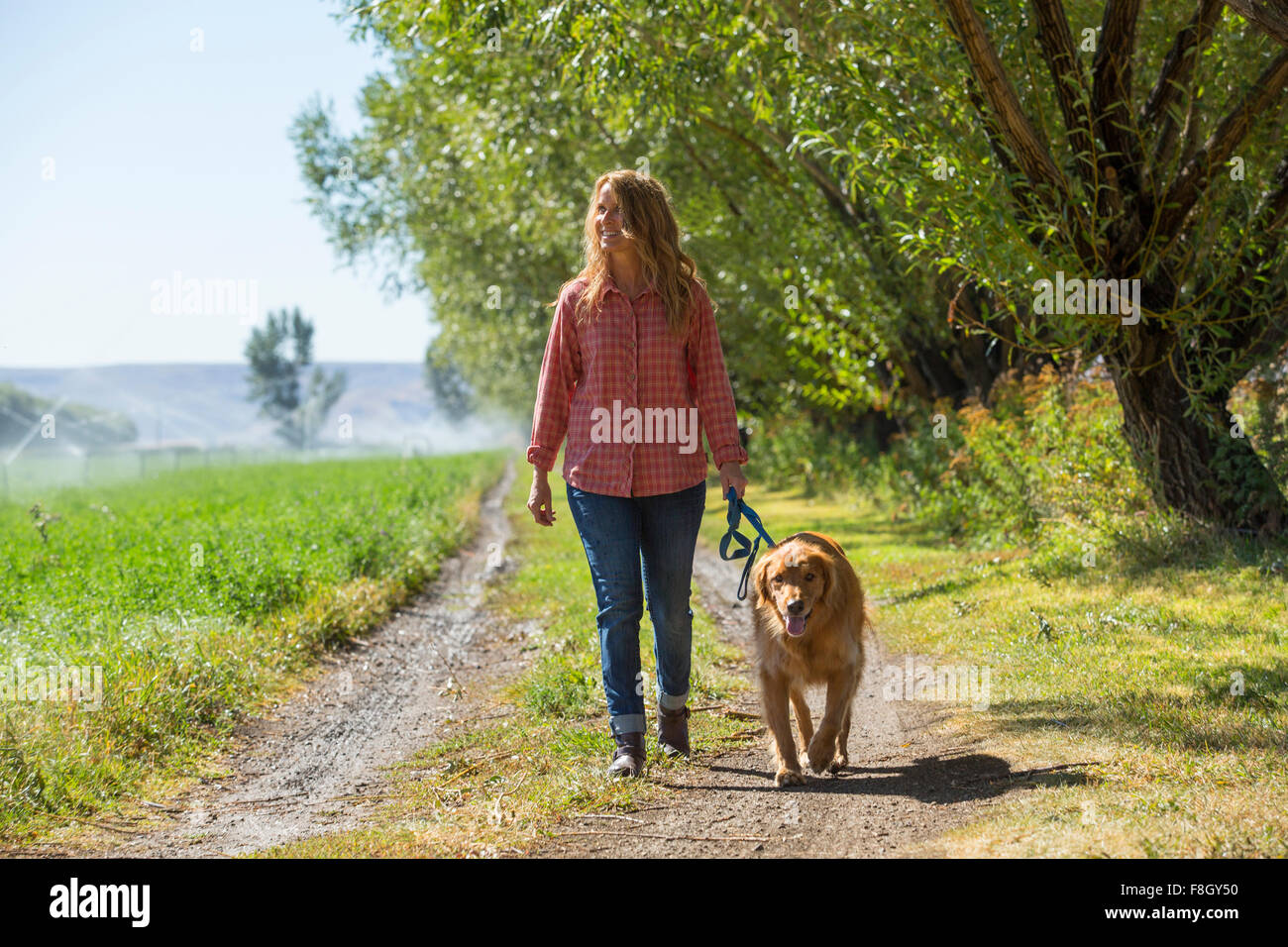 Mujer caucásica caminar perro en camino de tierra Foto de stock