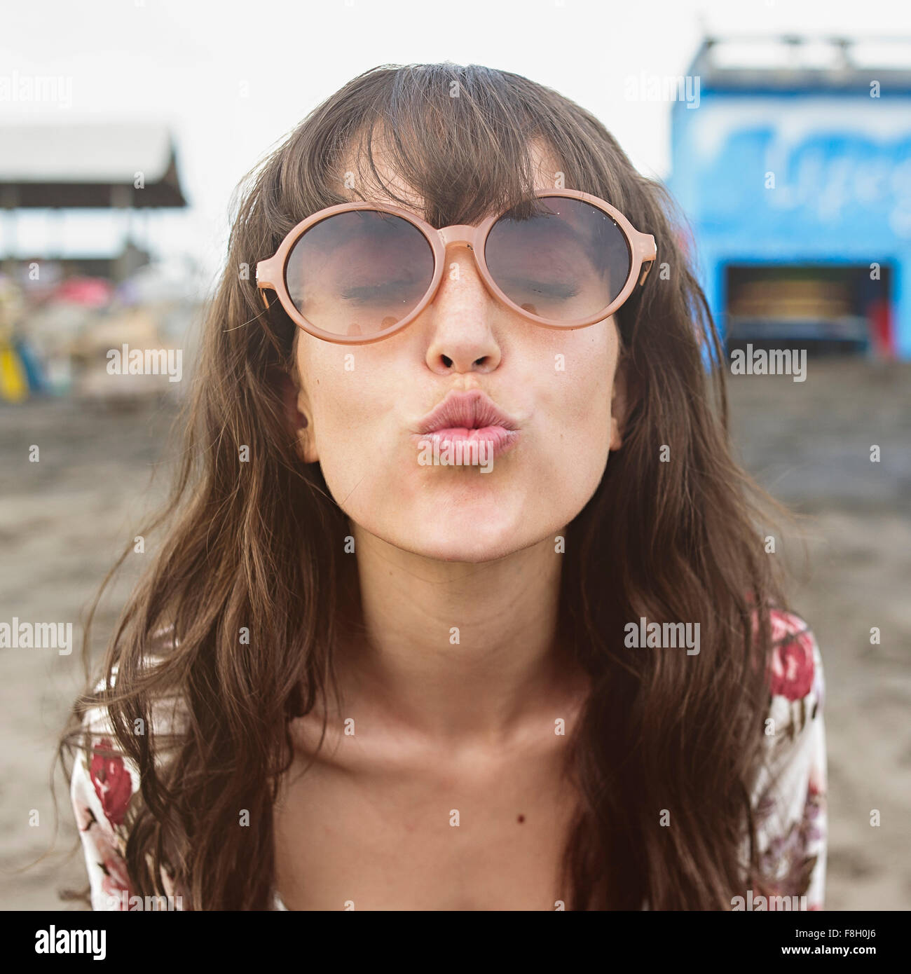 Mujer caucásica en gafas de sol arruga para besar a la playa Foto de stock