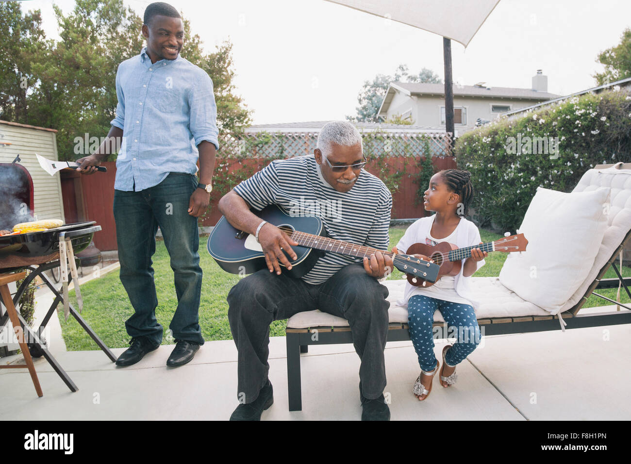 Nieta de abuelo afroamericano enseñando a tocar la guitarra Foto de stock