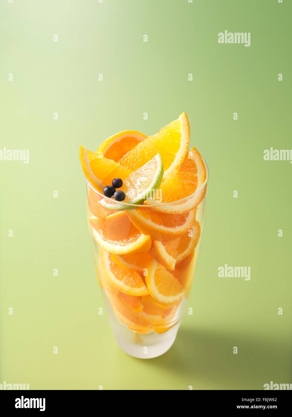 Los ingredientes en el vaso de naranja, limón y bayas de enebro jugo de frutas Foto de stock