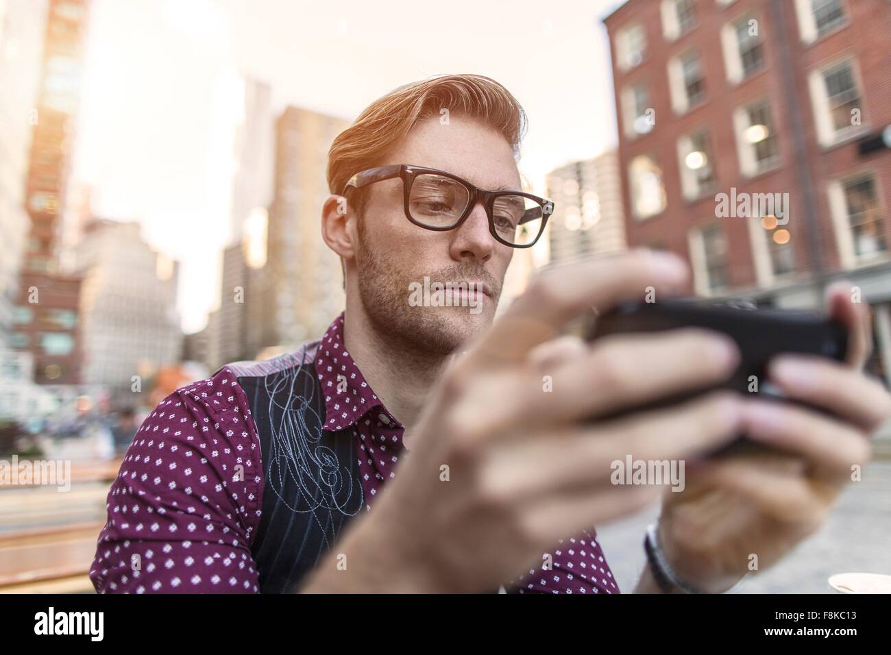 Joven empresario serio smartphone leer texto en café en la acera, Nueva York, EE.UU. Foto de stock