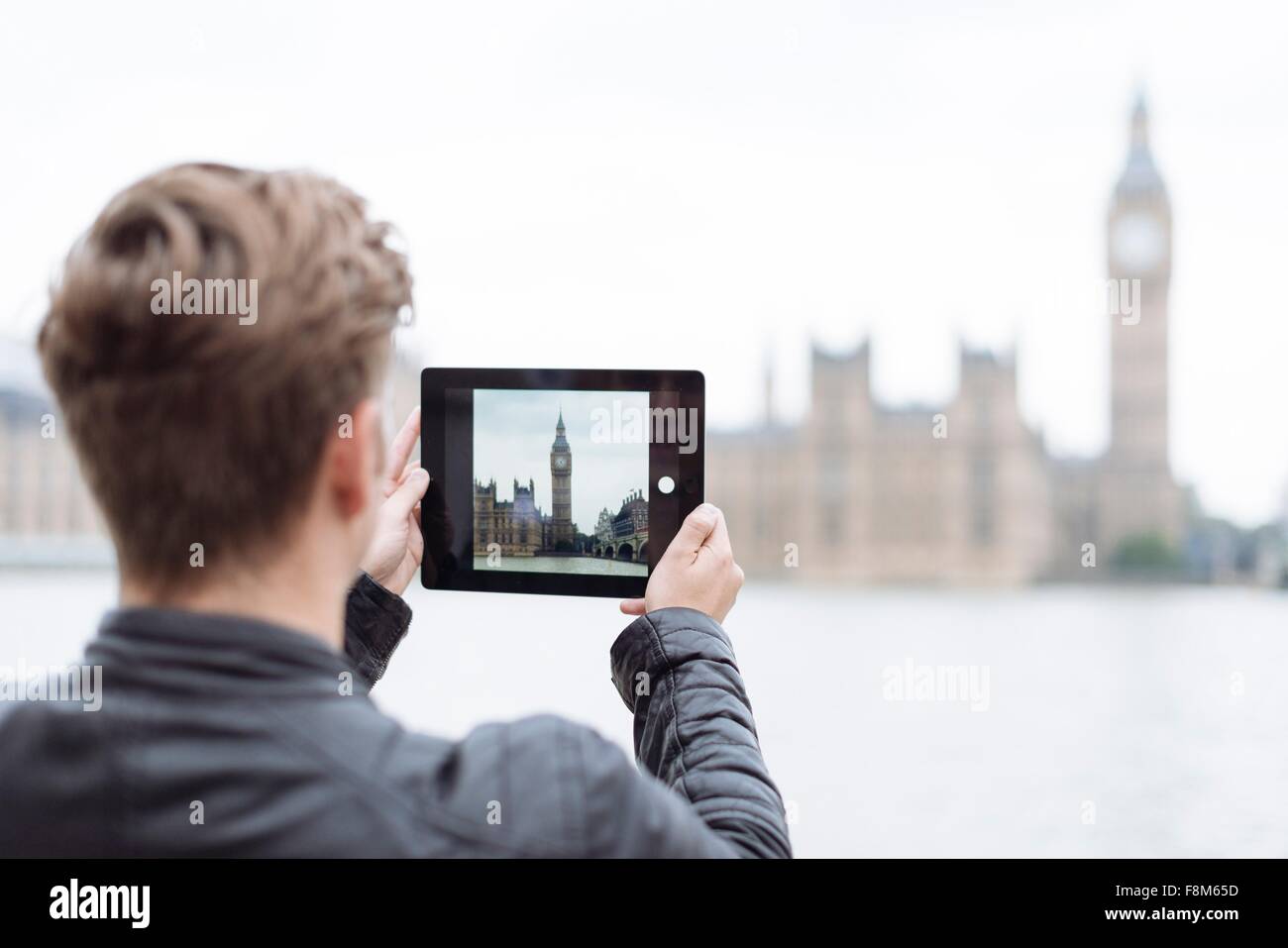 Vista trasera del joven fotografiar el Big Ben en tableta digital, Londres, Inglaterra, Reino Unido. Foto de stock