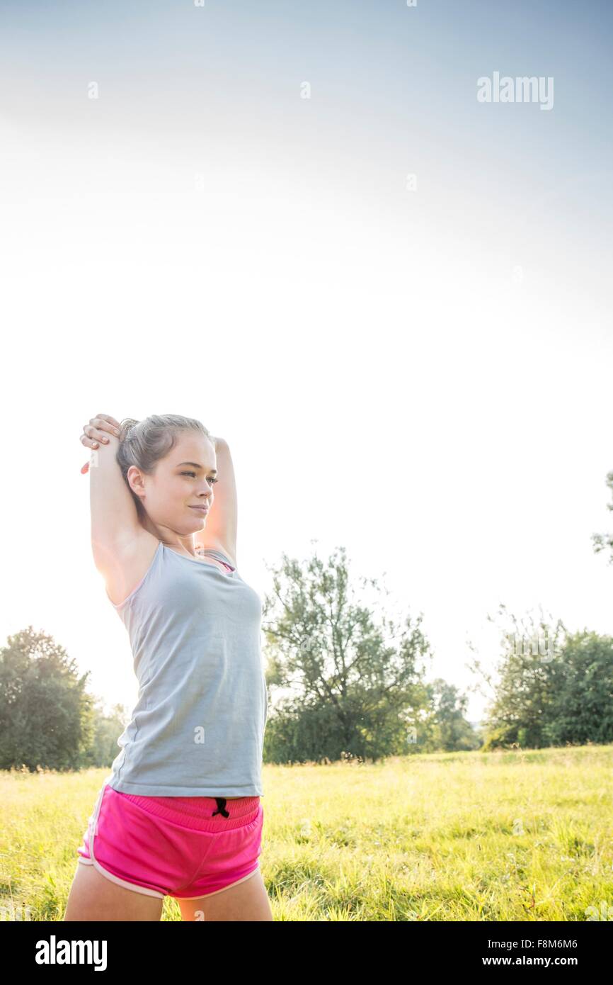 Mujer joven ejercicio, estiramiento en el campo Foto de stock