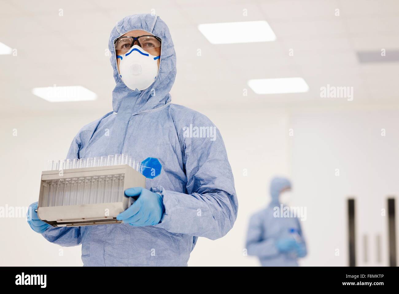 Scientist llevando una bandeja de tubos de ensayo en laboratorio Foto de stock