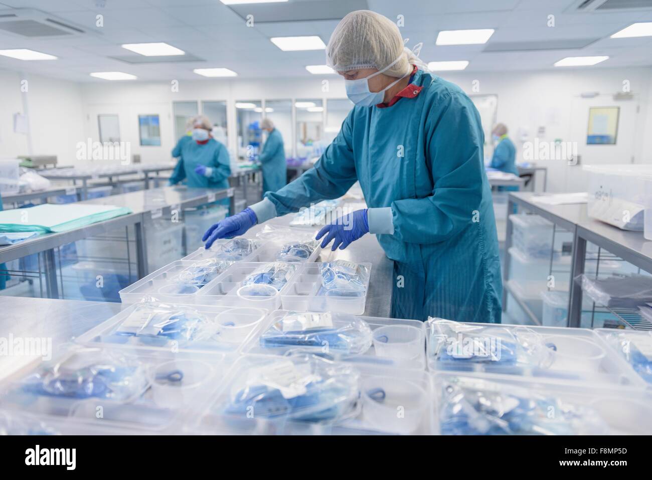 Los trabajadores empaque instrumental quirúrgico en sala limpia de fábrica de instrumentos quirúrgicos Foto de stock