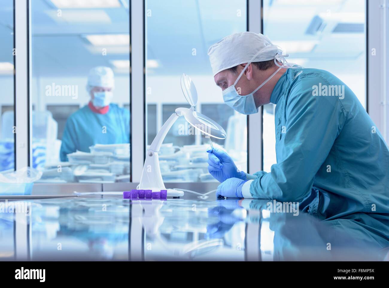 Los trabajadores inspeccionando los instrumentos quirúrgicos en sala limpia de fábrica de instrumentos quirúrgicos Foto de stock