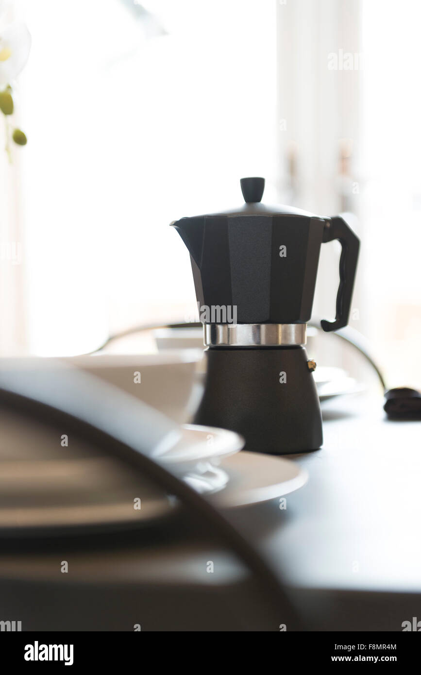 Una cafetera espresso en una mesa de desayuno. Foto de stock
