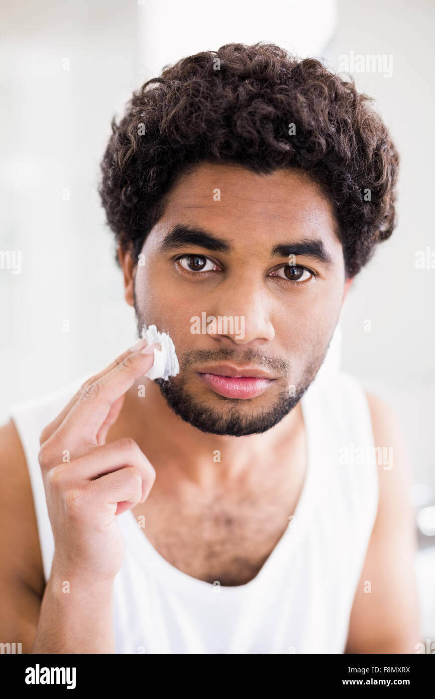 Hombre serio poner espuma de afeitar en su rostro. Foto de stock