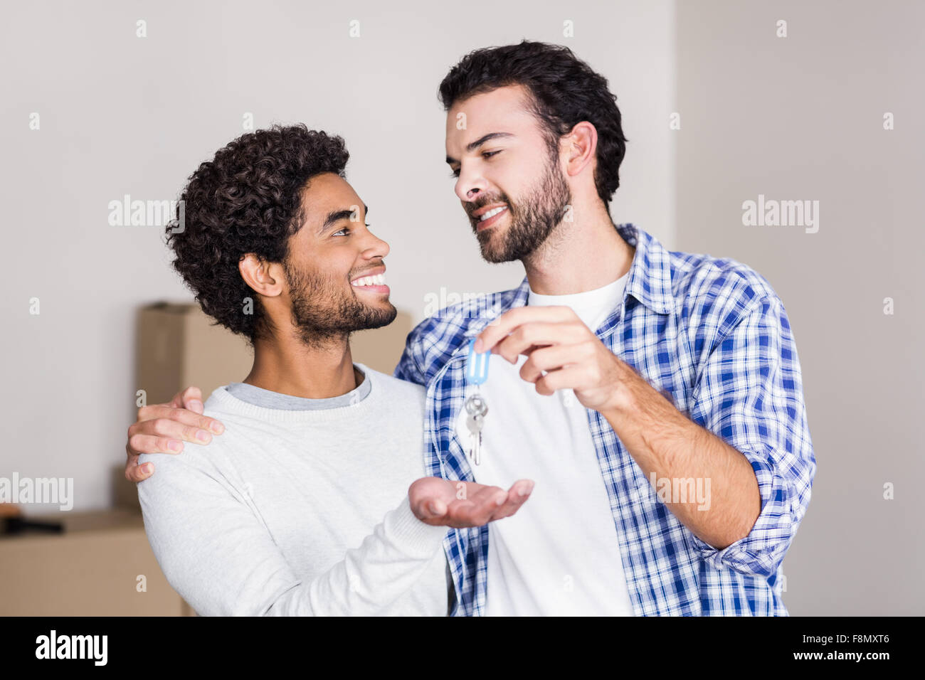 Feliz pareja gay celebrar nuevas llaves de casa Foto de stock