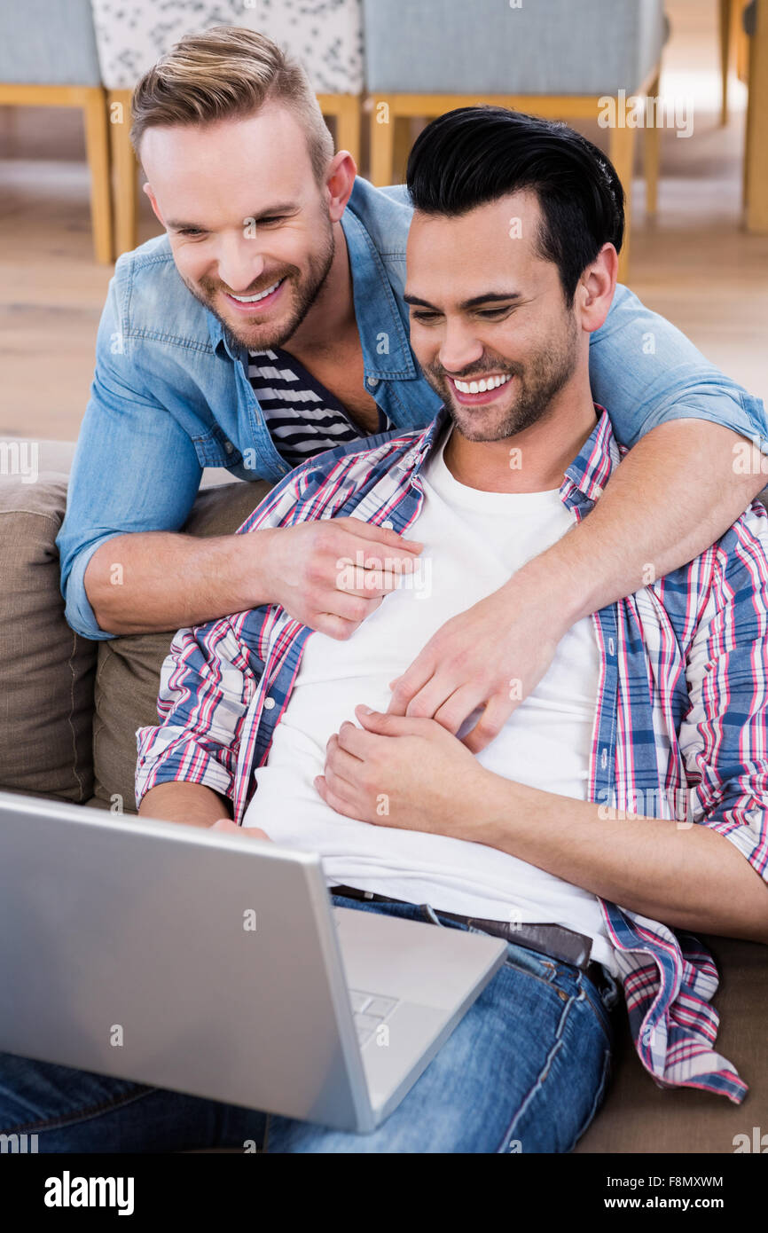 Una pareja gay relajado en el sofá con el portátil Foto de stock