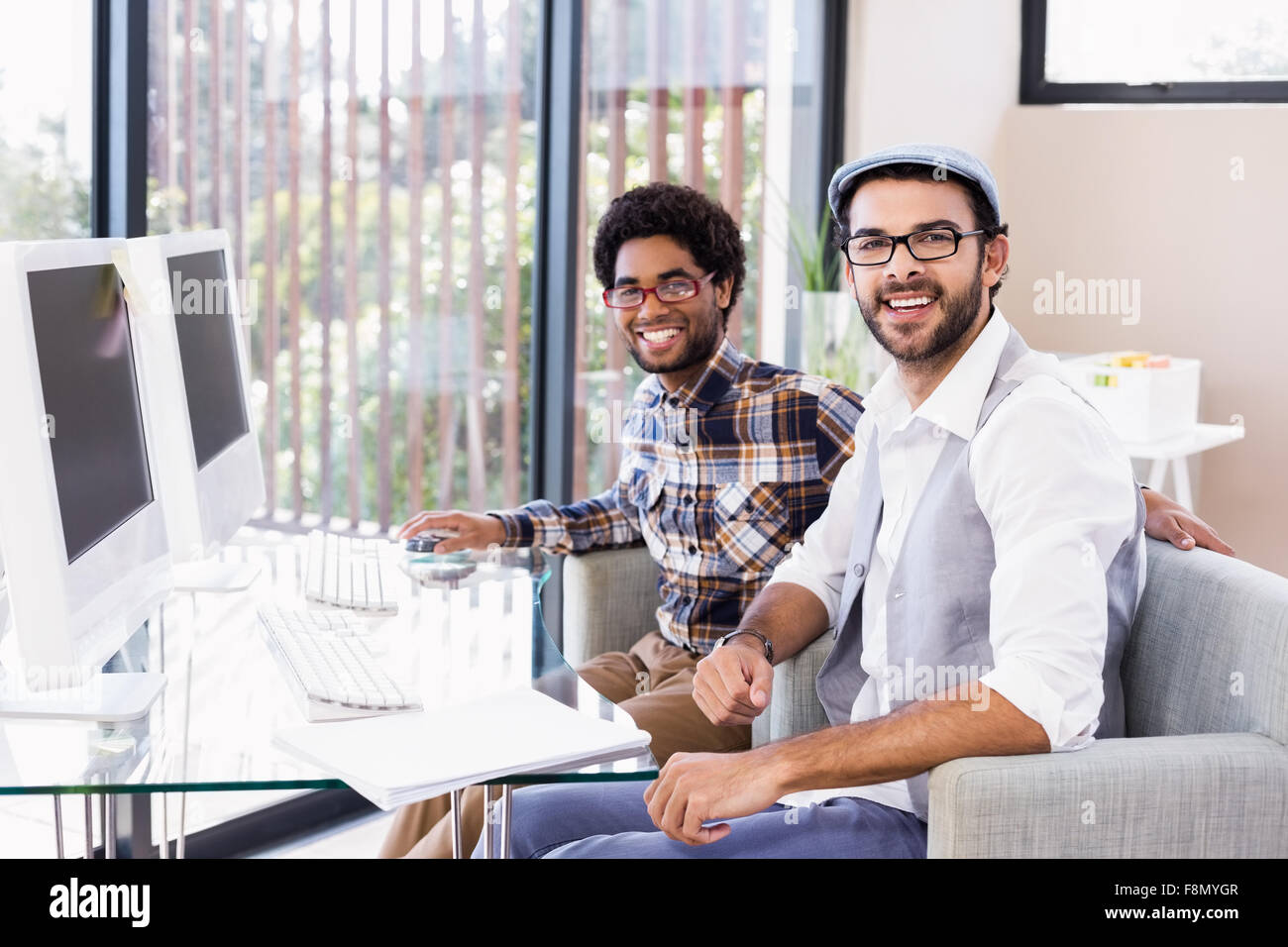 Una pareja gay sonriente sentado en el escritorio Foto de stock