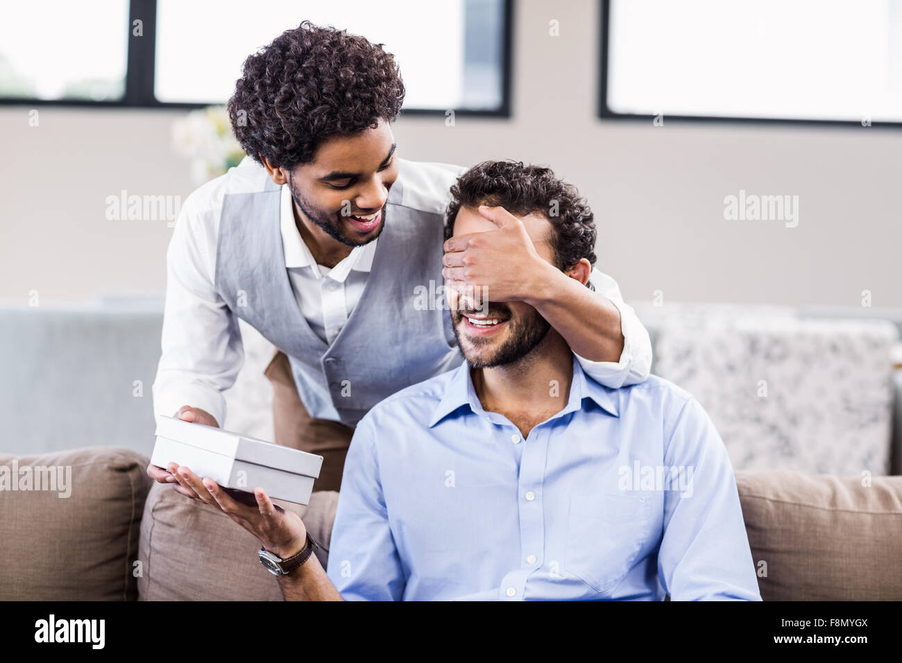 Guapo cubriendo novios ojos y dar un regalo Foto de stock