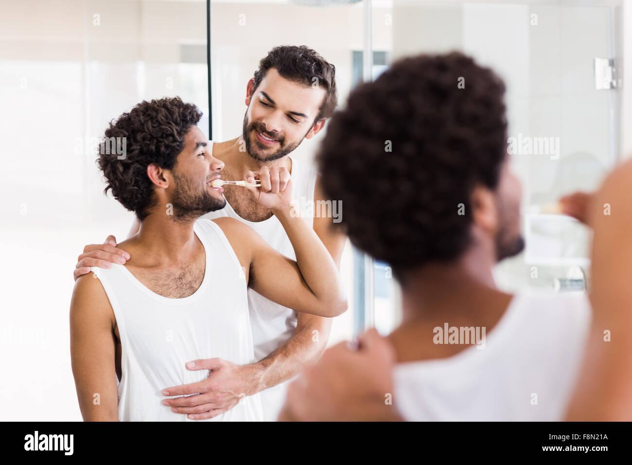 La reflexión de la feliz pareja gay en el baño. Foto de stock