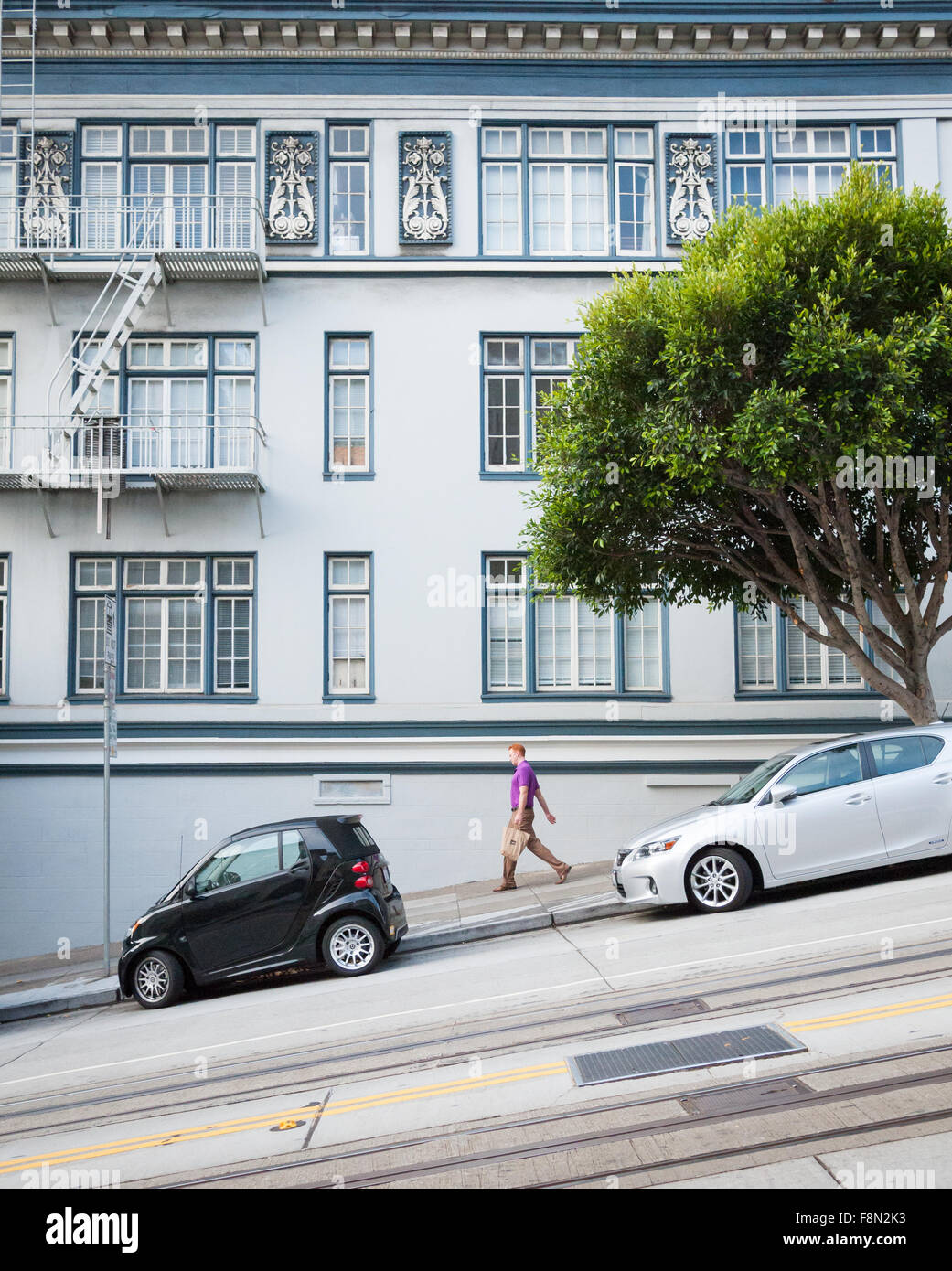 Un hombre camina por una pendiente pronunciada en California Street, en el corazón de San Francisco, California. Foto de stock