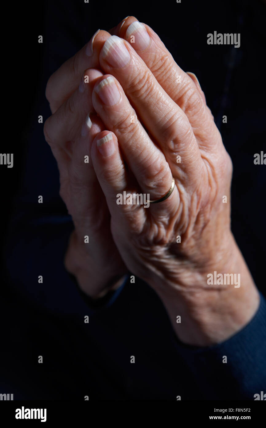 Mujer Senior las manos entrelazadas en la oración Foto de stock