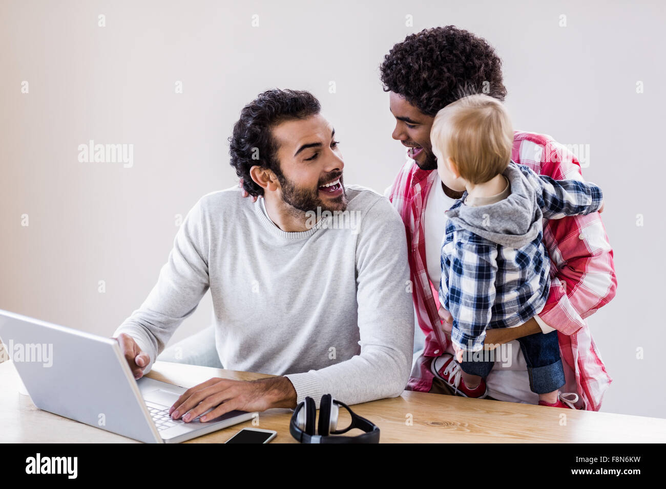 Feliz pareja gay con el niño utilizando el portátil Foto de stock