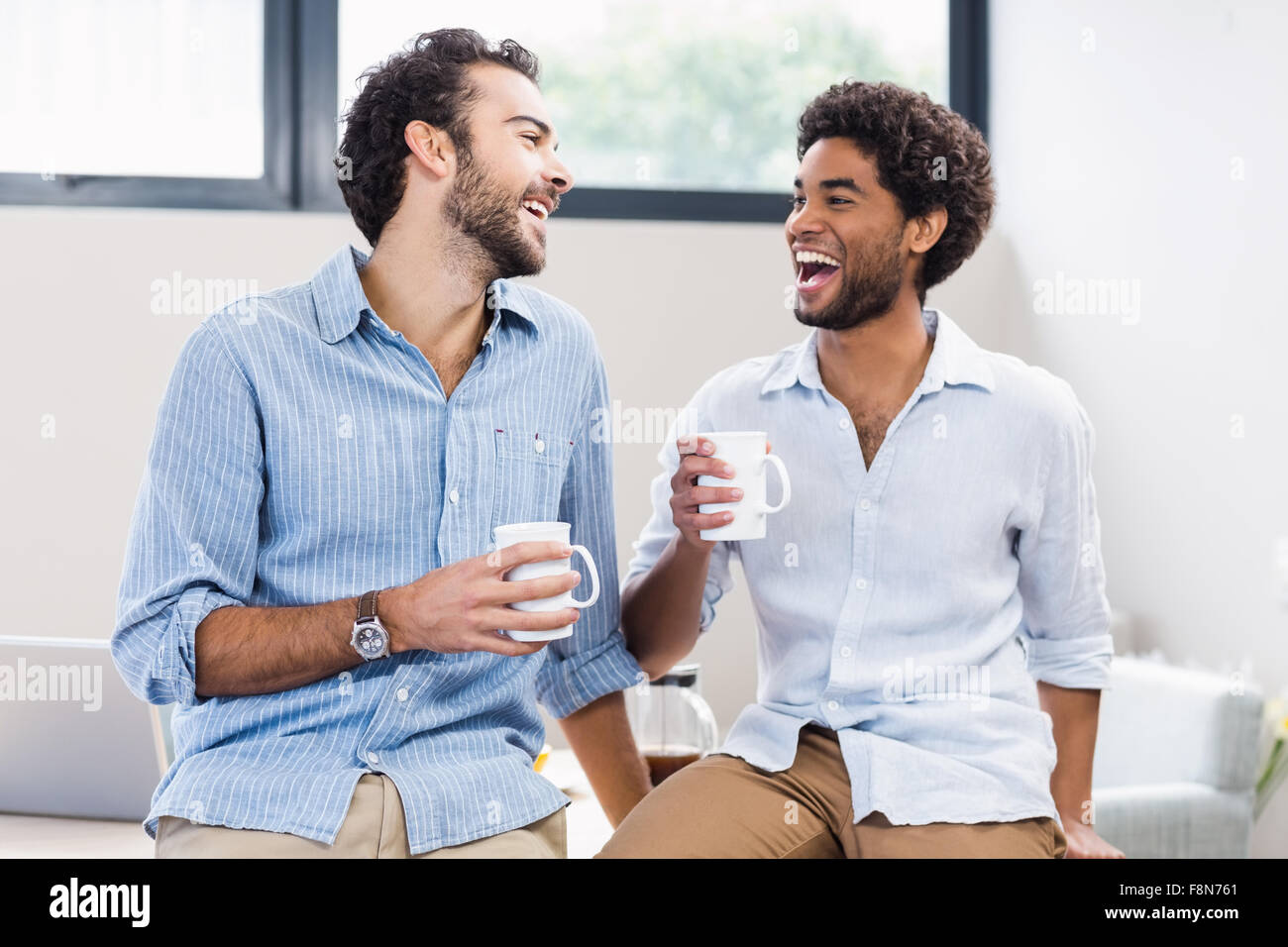 Feliz pareja gay celebración copas y riendo Foto de stock