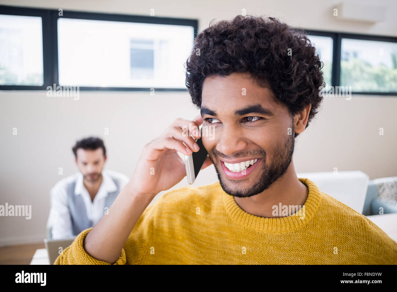 Hombre sonriente en la llamada telefónica con la pareja en segundo plano. Foto de stock