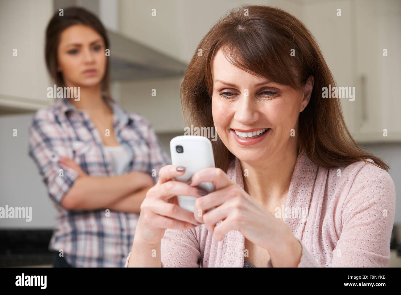 Madre utilizando el teléfono móvil con su hija adolescente frustrado Foto de stock