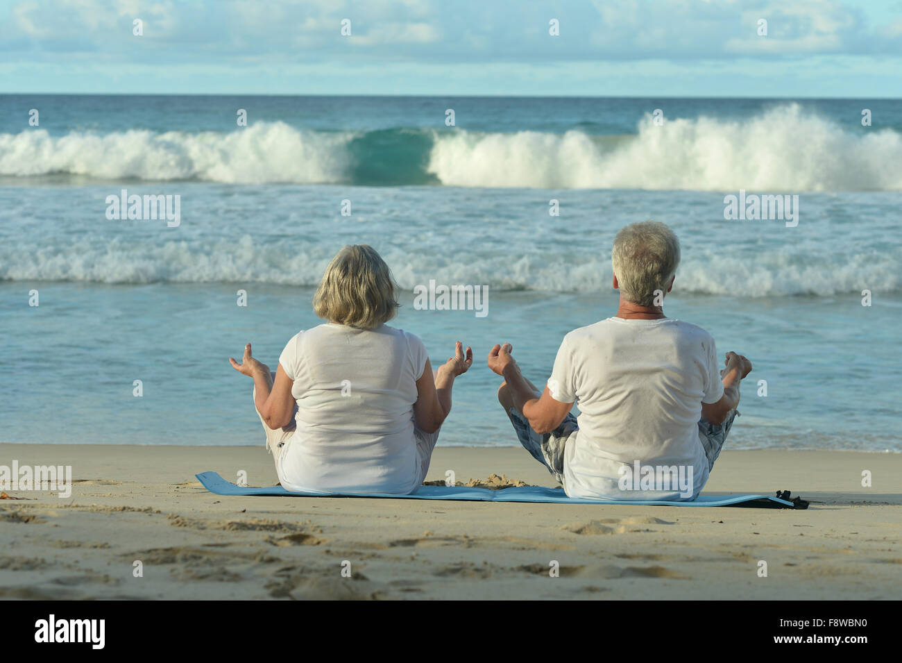Pareja de ancianos meditar en la playa Foto de stock